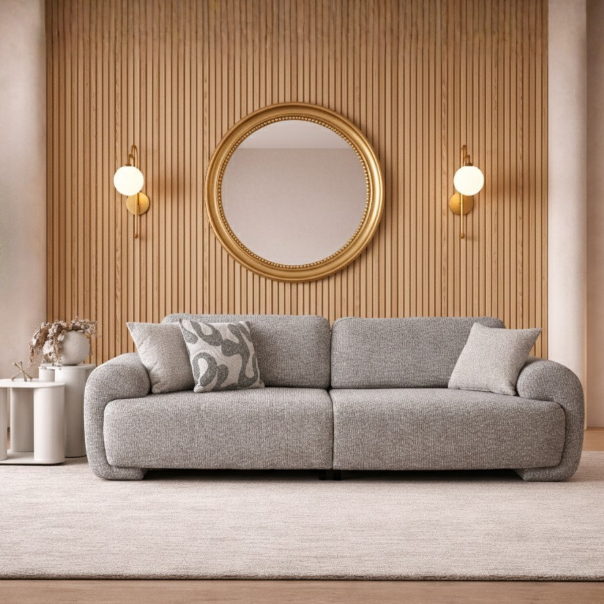 Gray sofa with decorative pillows in a living room setting with a gold mirror and wall lights.